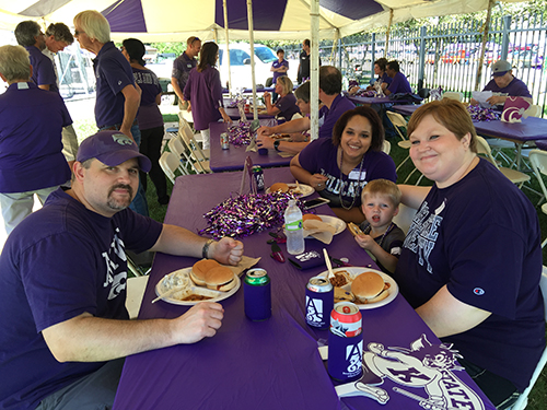 A multicultural family enjoying barbecue at an ArtSci tailgate.