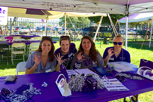 Student ambassadors making Wildcat hand sign at ArtSci tailgate