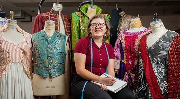 Bernie sitting on stool surrounded by elaborate costumes