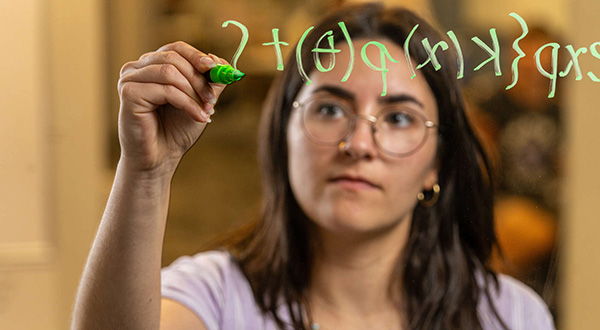 Duru writes equation on glass that viewer sees through