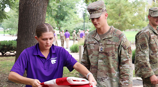 uniformed cadet watches newer cadet folding American flag